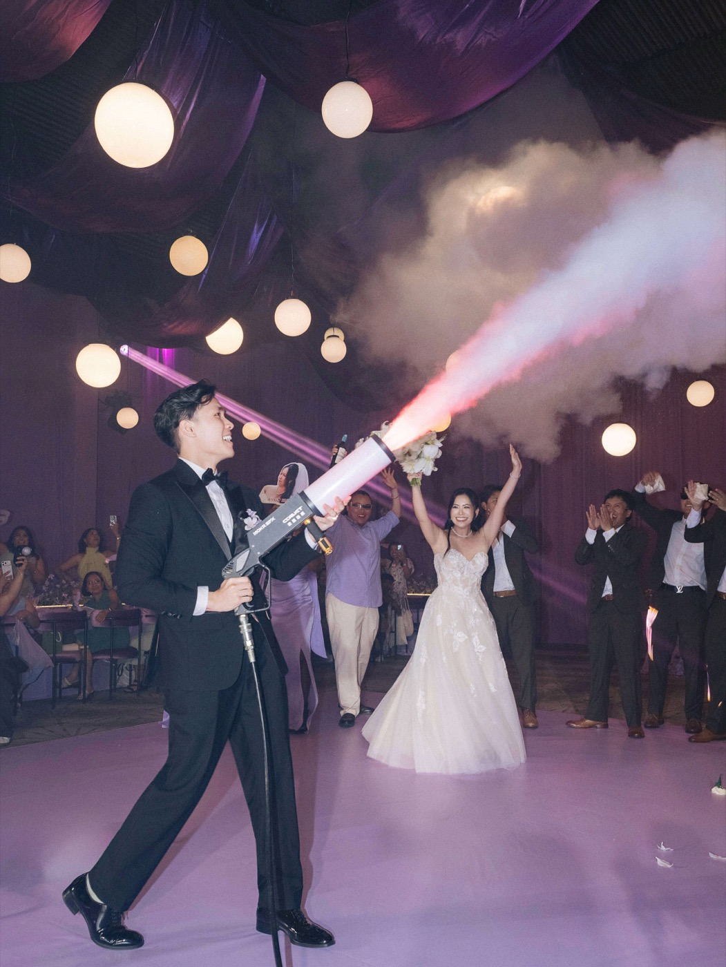 Groom firing a CO2 cannon as the bride dances behind him